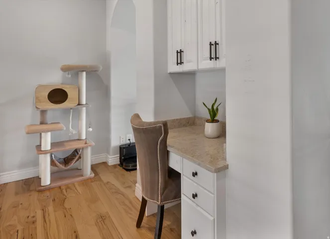 Flex loft space with Integrated desk area featuring white cabinetry with dark hardware, a speckled countertop, and wood-finish flooring
