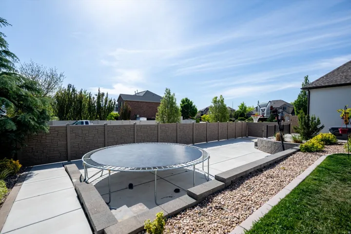 Expansive backyard featuring a concrete patio, decorative rock landscaping, and a substantial privacy fence