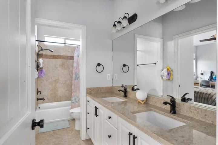 Full bathroom with dual vanity with integrated sinks, light-toned countertop, and matte black fixtures