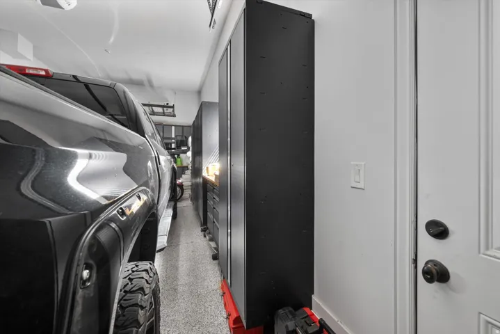 Garage featuring a durable speckled floor, bright overhead lighting, and built-in storage cabinetry