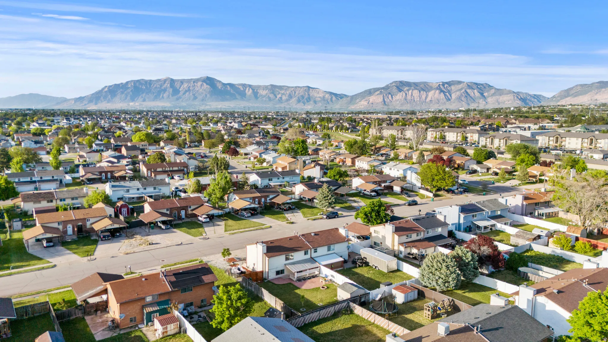 Expansive aerial perspective showcasing a residential neighborhood with distant mountain ranges