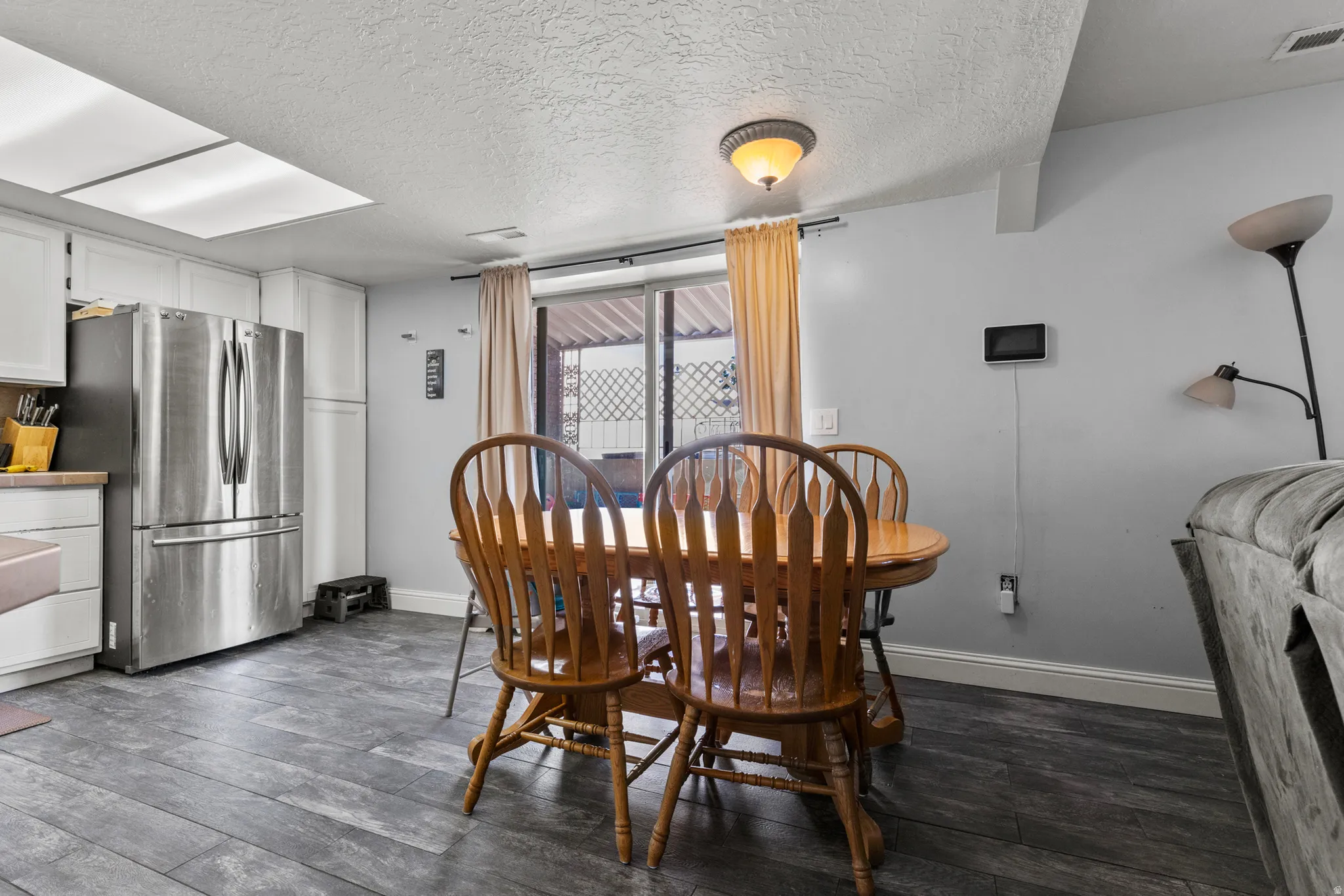 Open concept living space featuring wood-finish flooring, white cabinetry, and stainless steel appliances