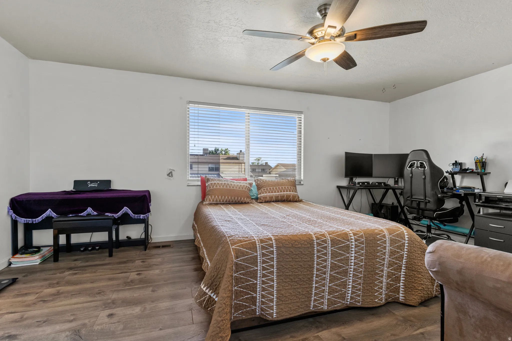 Bedroom featuring wood-finish flooring, a ceiling fan with integrated lighting, and a window with horizontal blinds