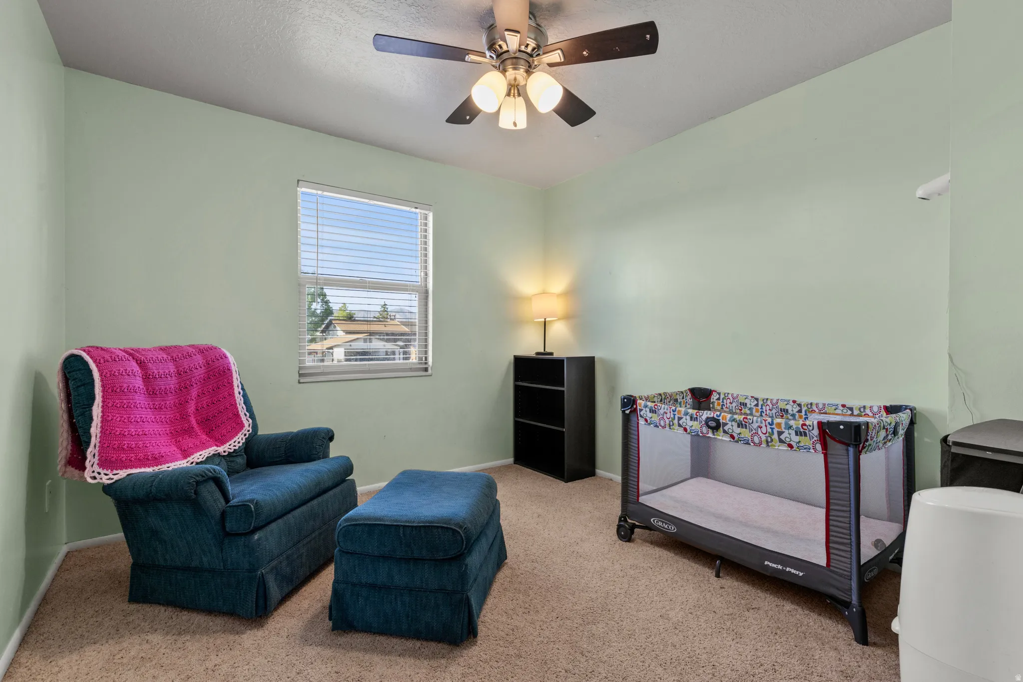 Carpeted room featuring a ceiling fan, window with blinds, and light green wall paint