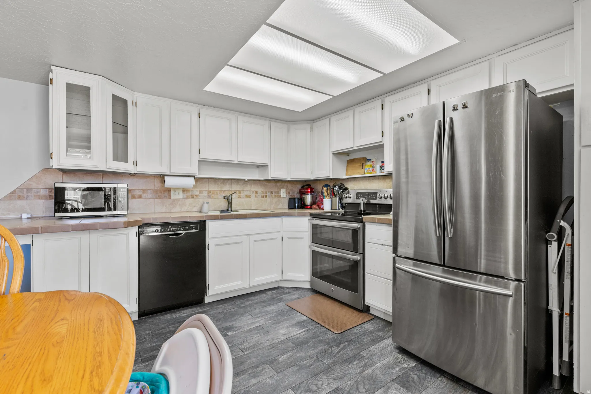 Kitchen featuring white cabinetry, wood-finish flooring, stainless steel French door refrigerator, and a double oven range