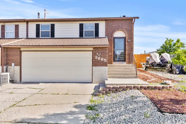 Brick and siding exterior featuring a two-car garage, concrete driveway, and a front entry with concrete steps and metal railings