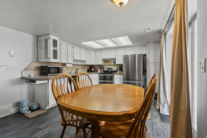 Kitchen featuring white cabinetry, stainless steel appliances, a tile backsplash, and wood-finish flooring