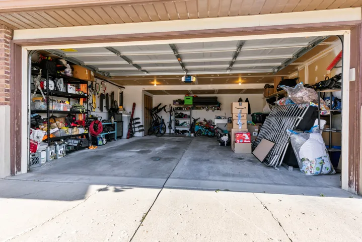 Spacious two-car garage with concrete flooring, illuminated by overhead lighting