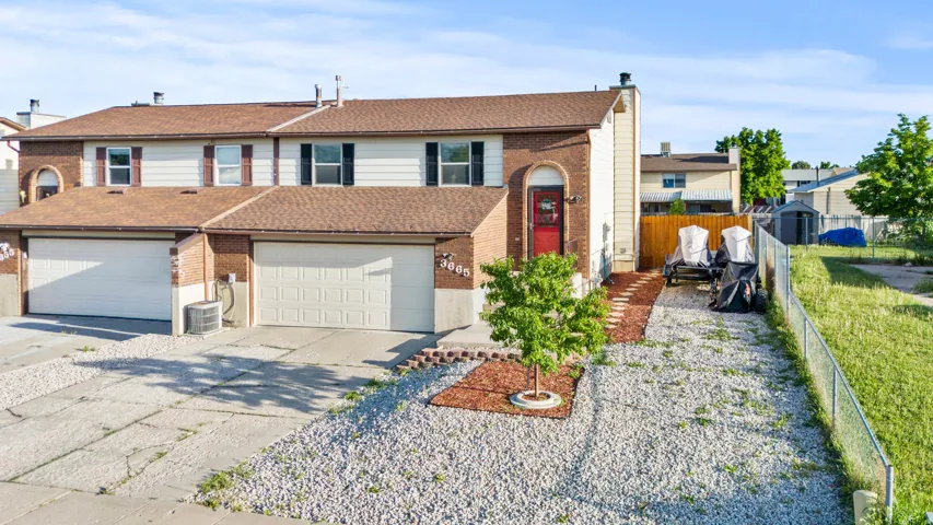Brick and siding exterior featuring a red entry door and two garage doors