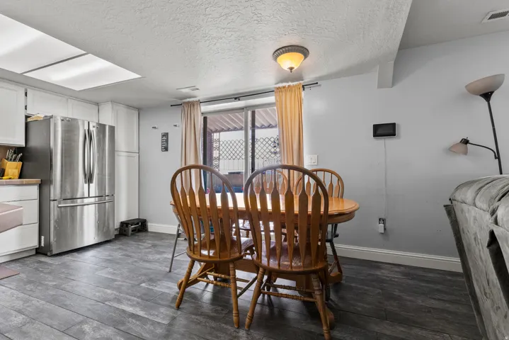 Open concept living space featuring wood-finish flooring, white cabinetry, and stainless steel appliances