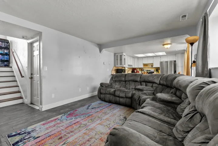 Open-concept living space featuring wood-finish flooring and a bright kitchen beyond