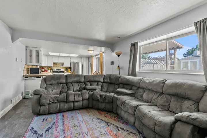 Living area featuring wood-finish flooring and a wide window with curtain rods