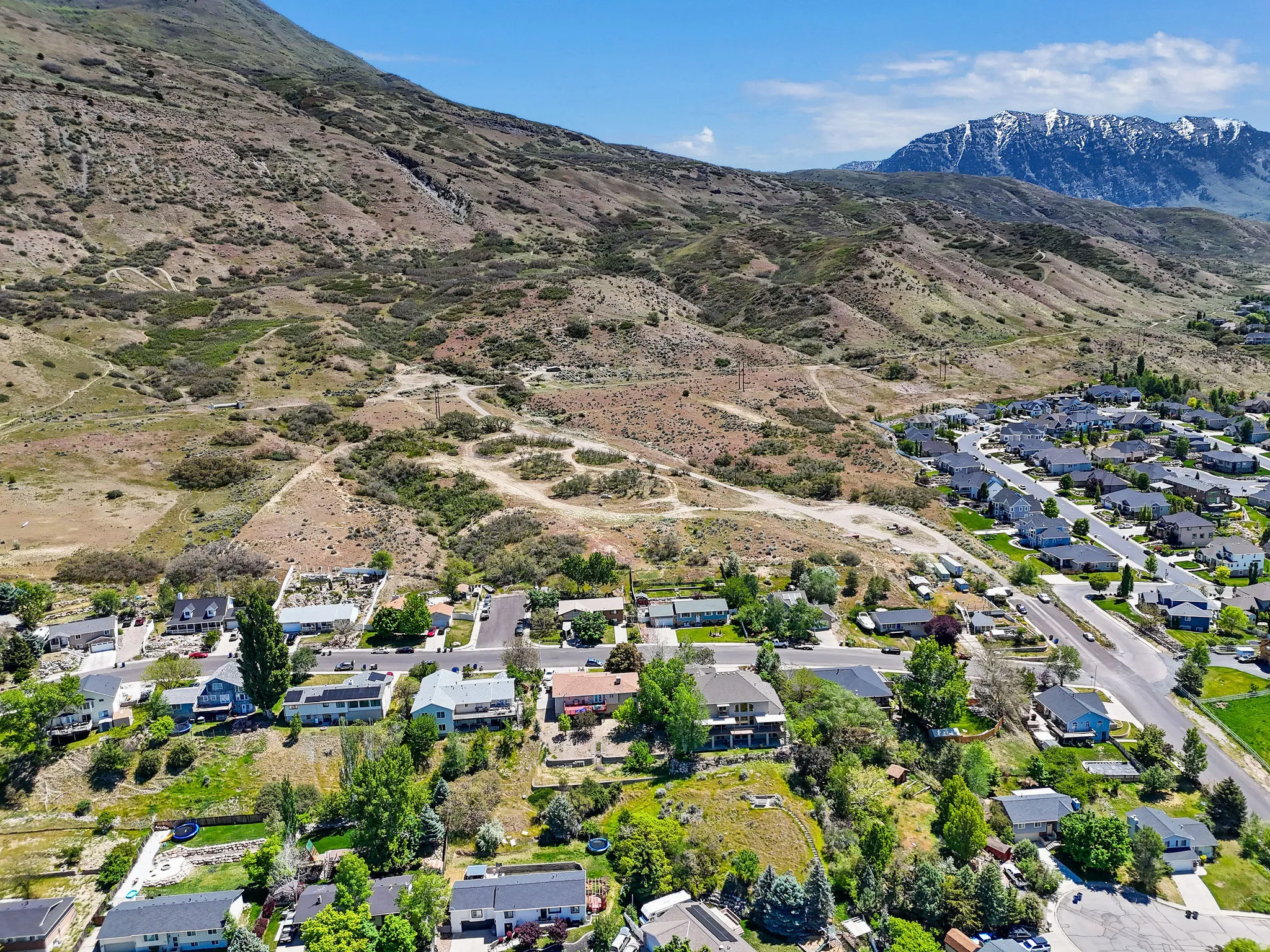 Aerial perspective showcasing residential properties nestled at the base of a rugged mountain range