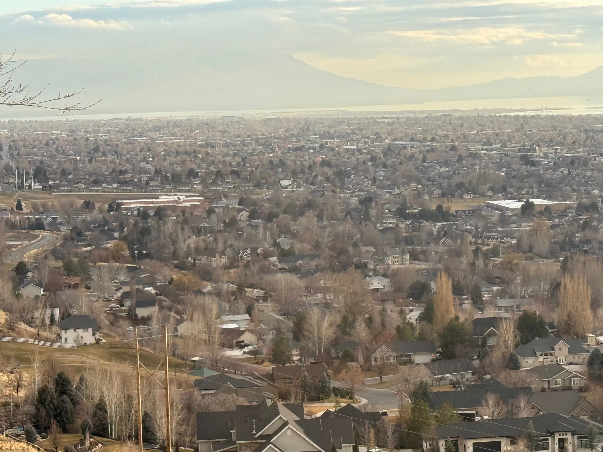 Expansive panoramic landscape featuring a distant body of water, distant mountains, and a vast residential area