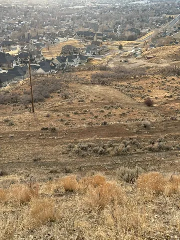 Sloping land featuring natural terrain with scattered brush and dry grasses