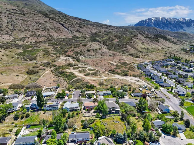 Aerial perspective showcasing residential properties nestled at the base of a rugged mountain range