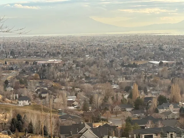 Expansive panoramic landscape featuring a distant body of water, distant mountains, and a vast residential area