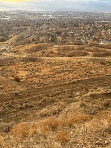 Expansive hillside property featuring natural terrain and distant urban and mountainous scenery