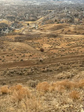 Sloping terrain with natural vegetation, offering distant urban and suburban scenery