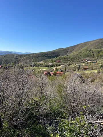 Panoramic hillside setting with distant residential structures and verdant landscape