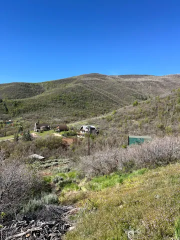 Expansive mountain terrain featuring natural vegetation and distant residential structures
