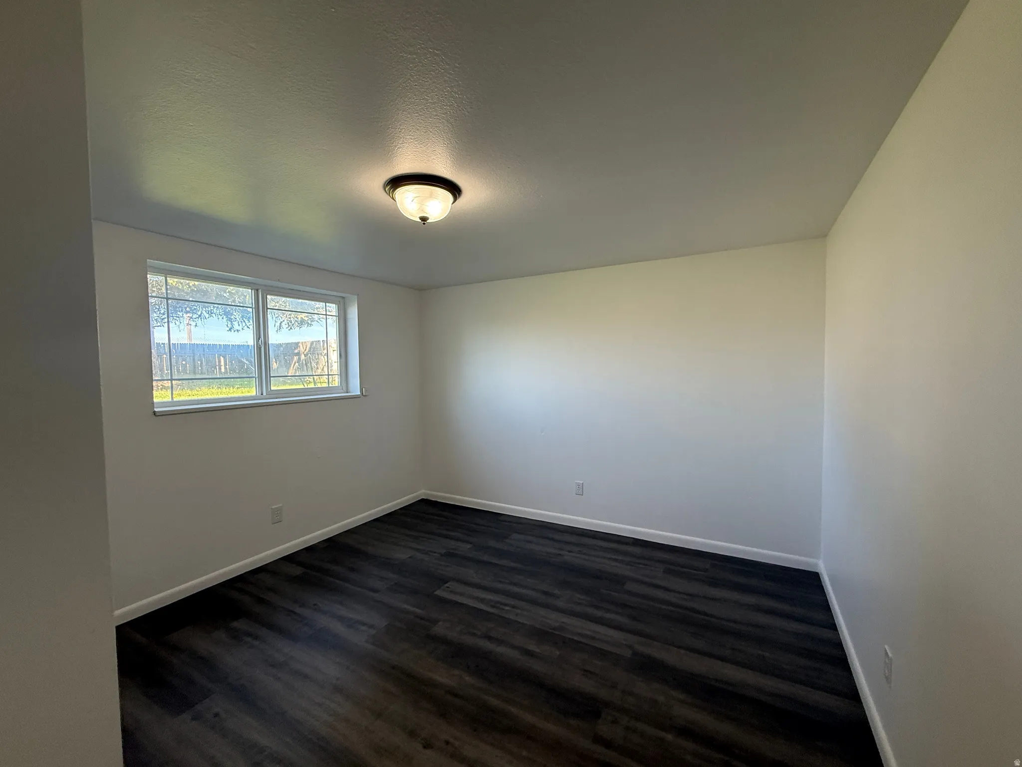 Bright interior space featuring wood-finish flooring, white baseboards, and a semi-flush mount ceiling light