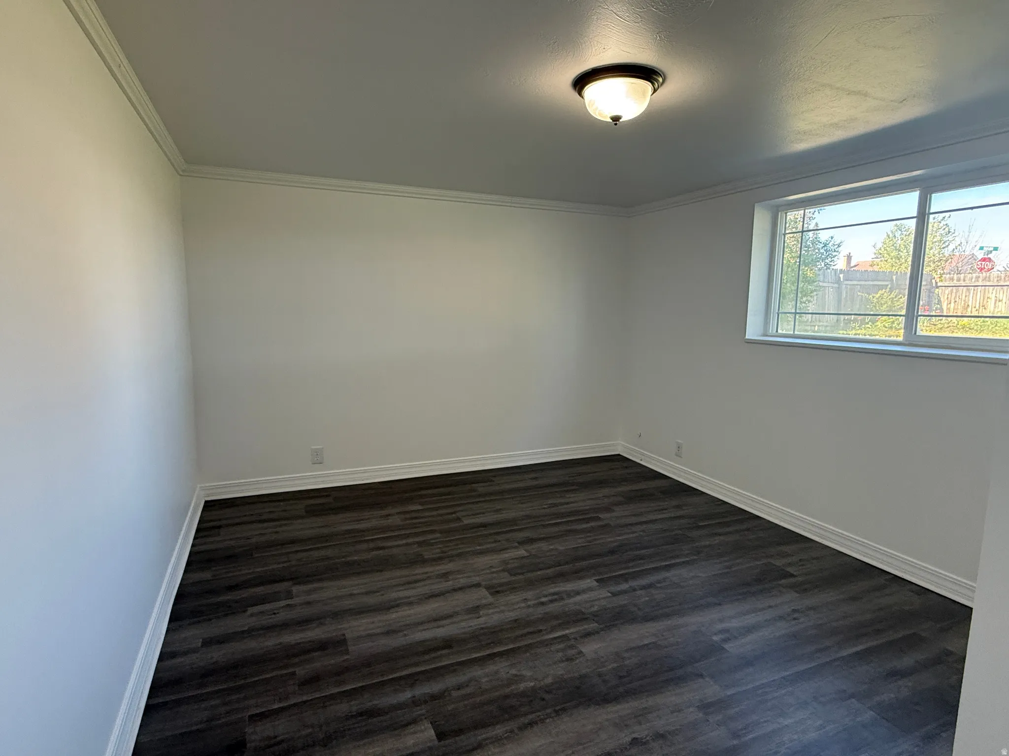 Room featuring wood-finish flooring, white walls, and a multi-pane window