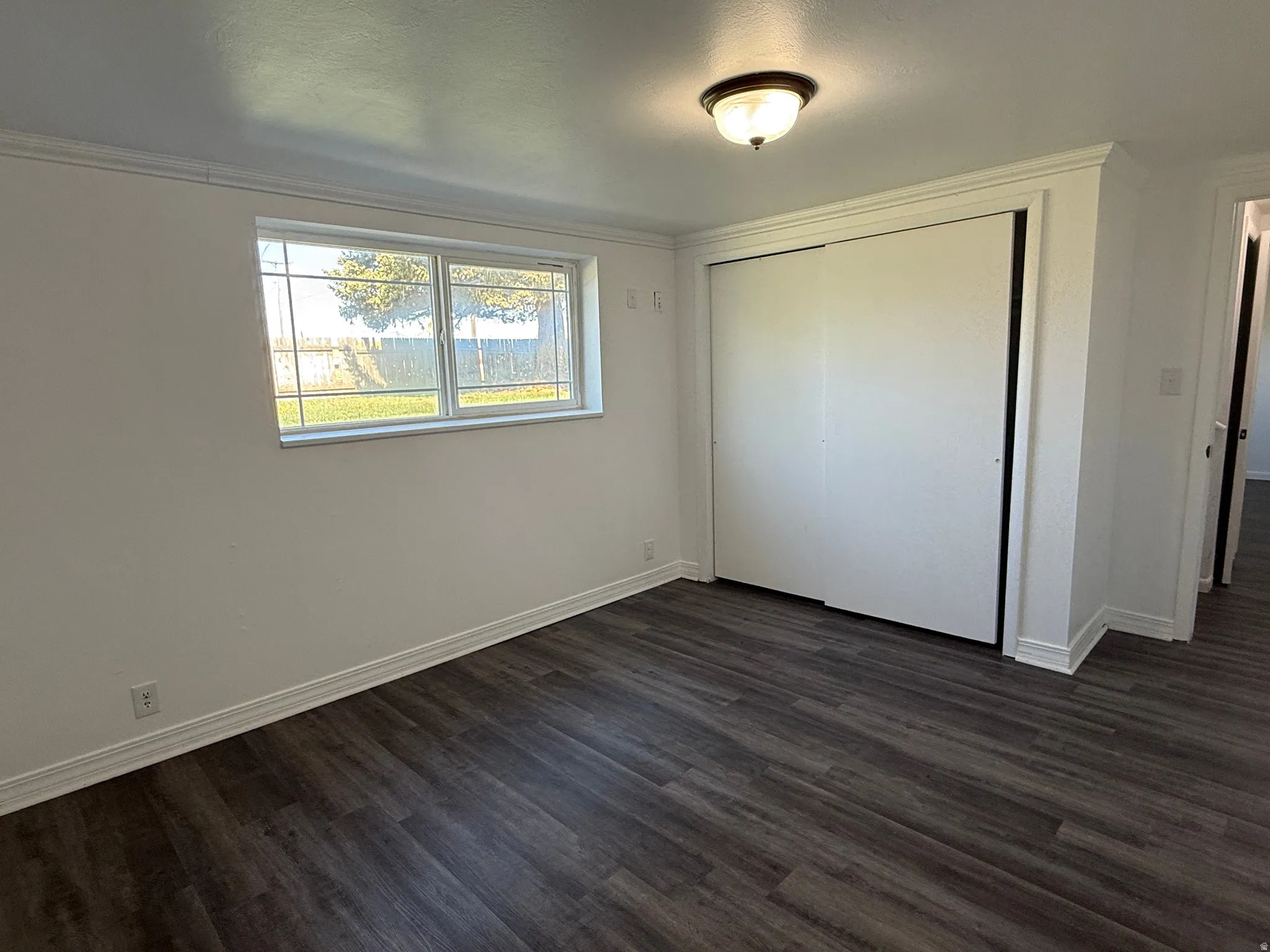 Room featuring wood-finish flooring, a window with exterior views, and a ceiling-mounted light fixture