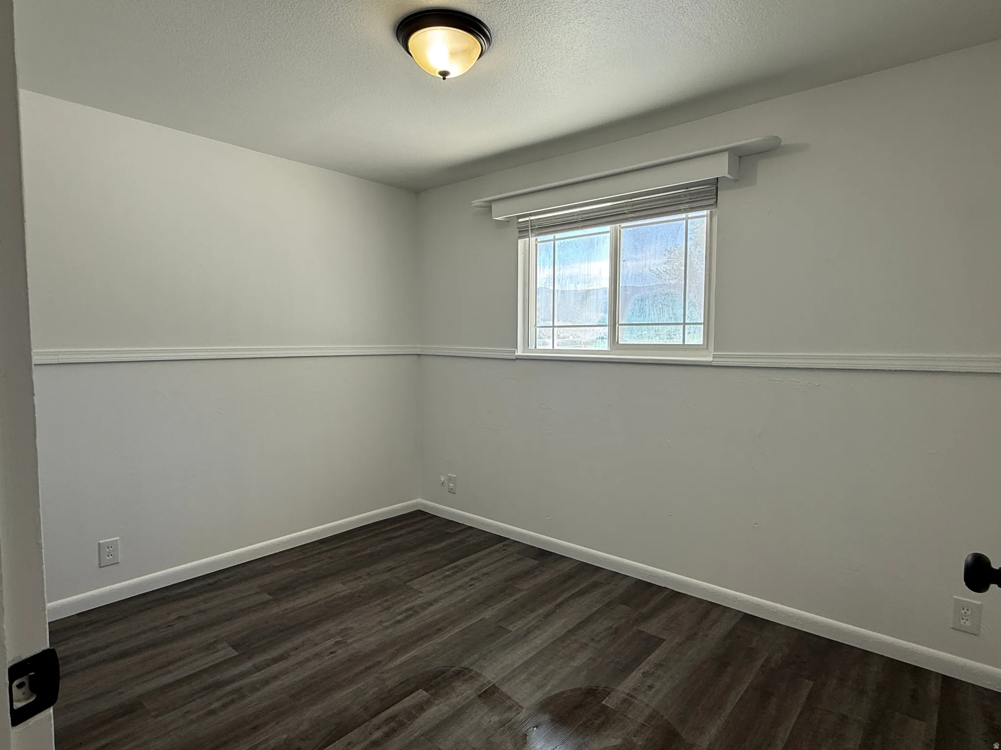 Interior room featuring wood-finish flooring and a single window with blinds