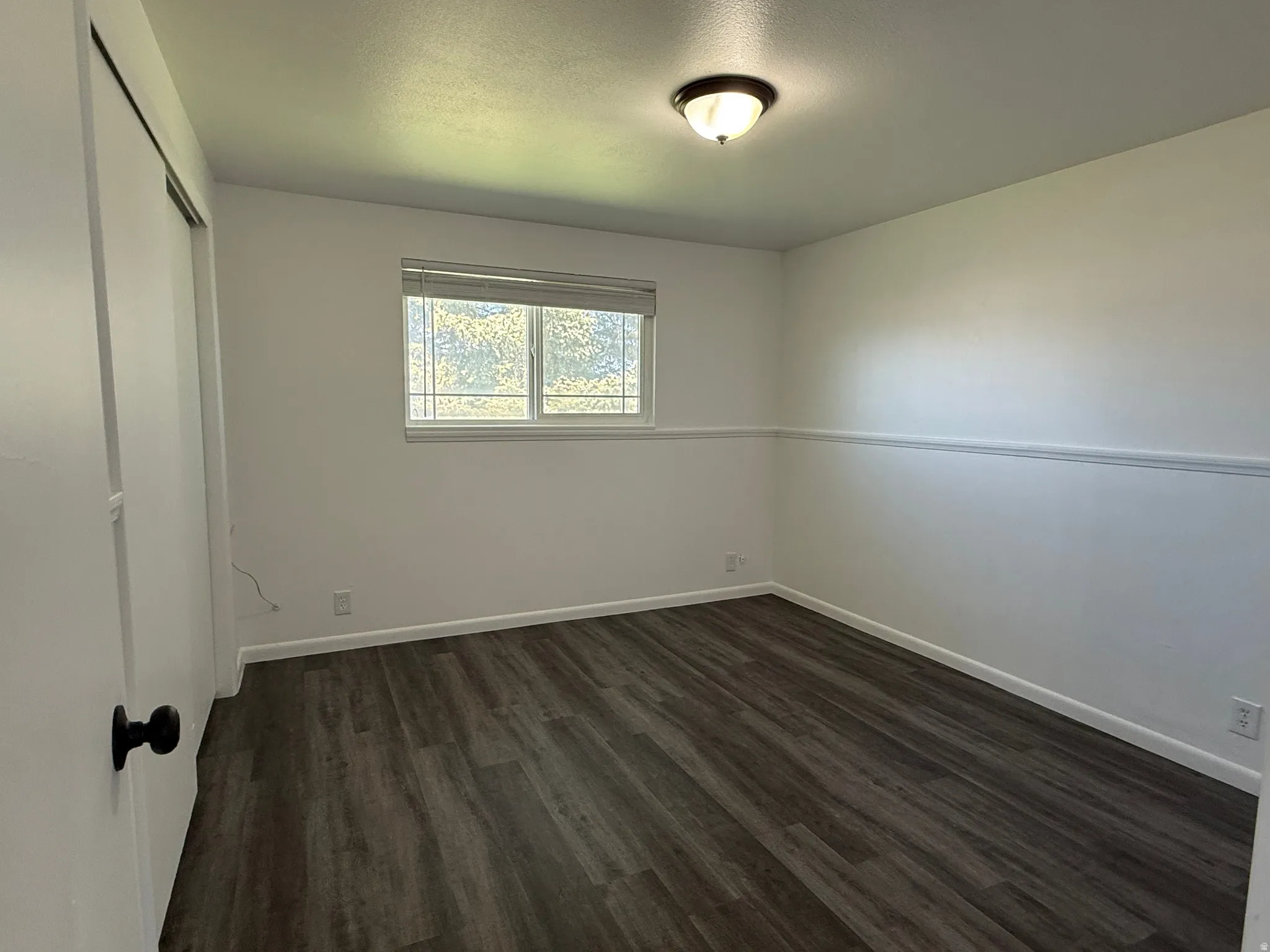 Bright room featuring wood-finish flooring, white walls, and a window with horizontal blinds
