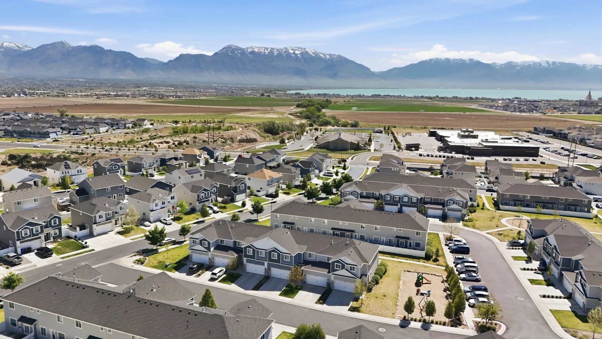 Expansive aerial view showcasing a residential community with diverse housing styles, including single-family homes and townhouses