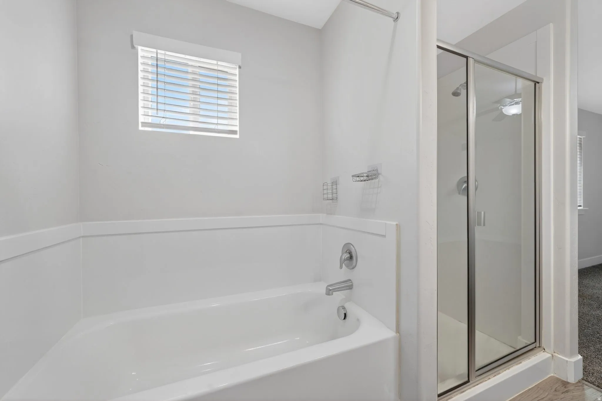 Bathroom featuring a built-in tub and separate glass-enclosed shower with chrome fixtures