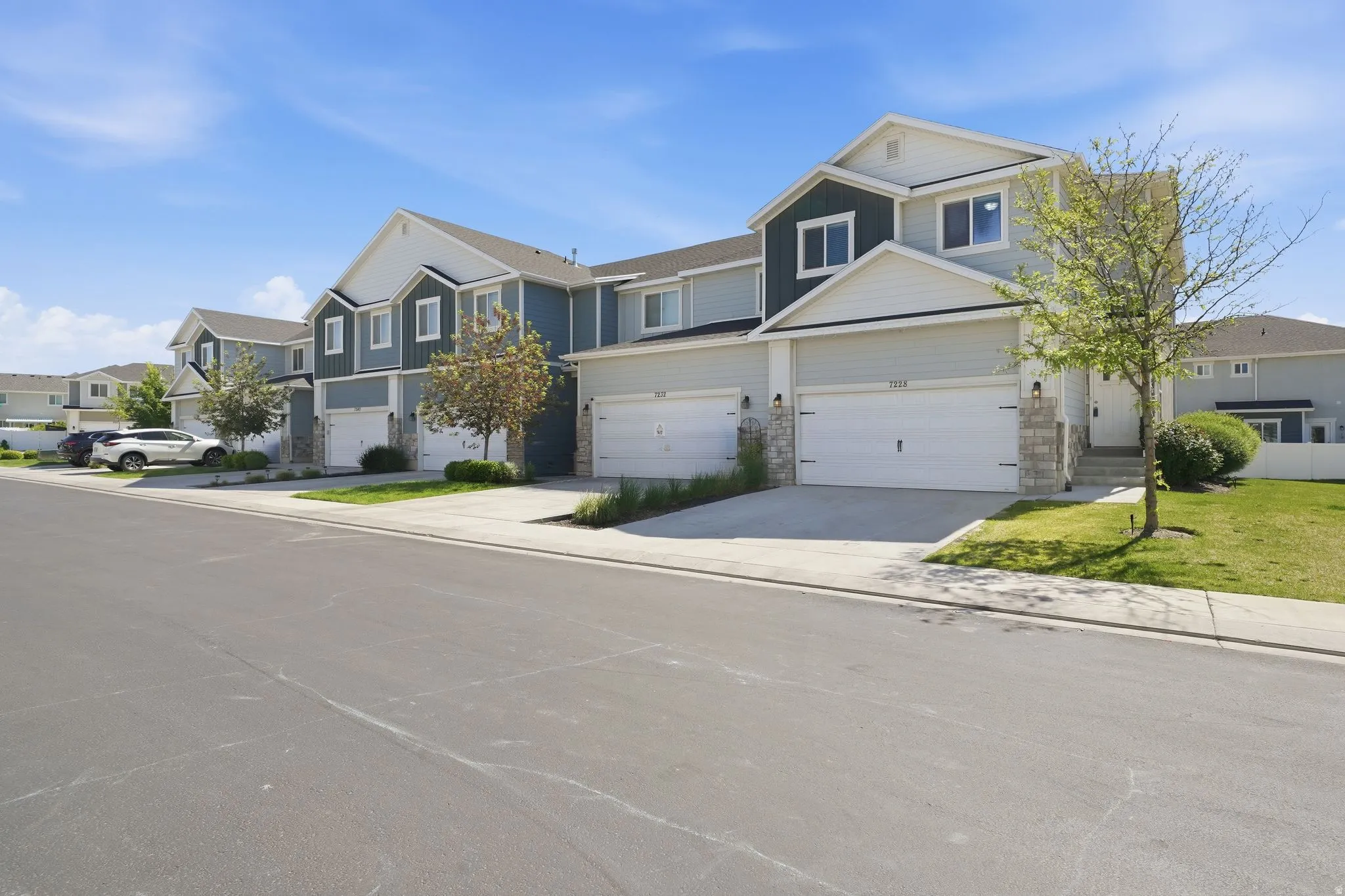 Modern townhome exterior with mixed siding, stone accents, and an attached two-car garage