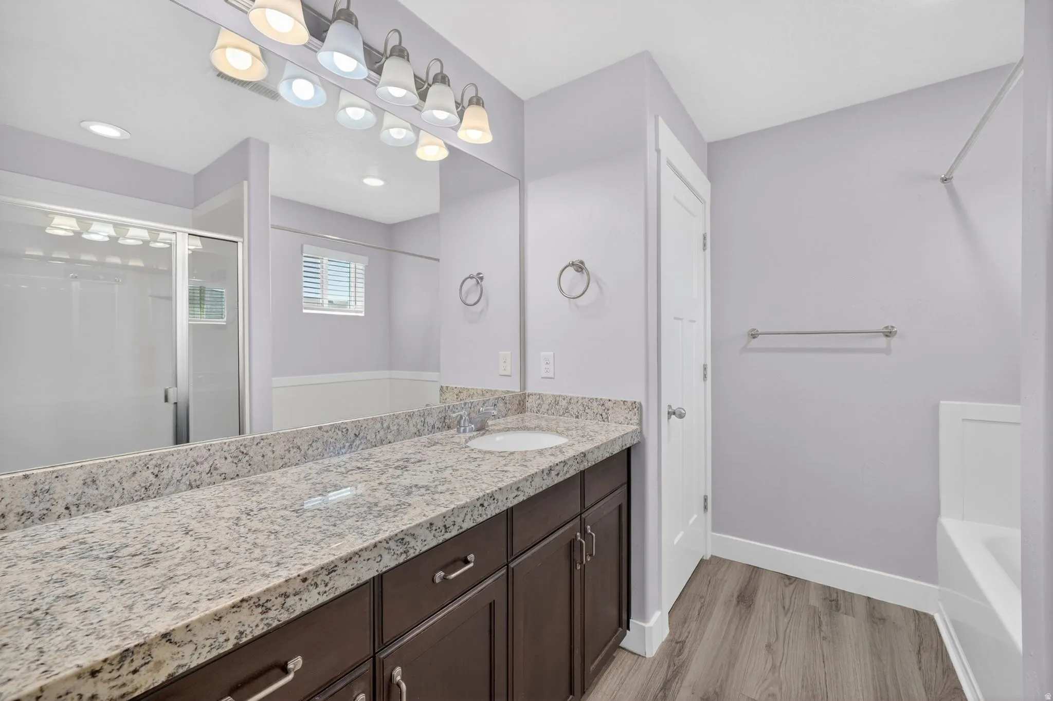 Expansive vanity with a light speckled countertop, dual under-mount sinks, and dark wood-finish cabinetry