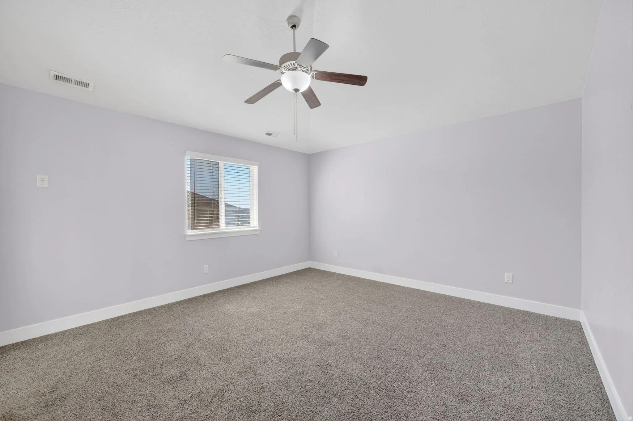 Carpeted room featuring a ceiling fan with light fixture, window with blinds, white baseboards, and light-toned walls