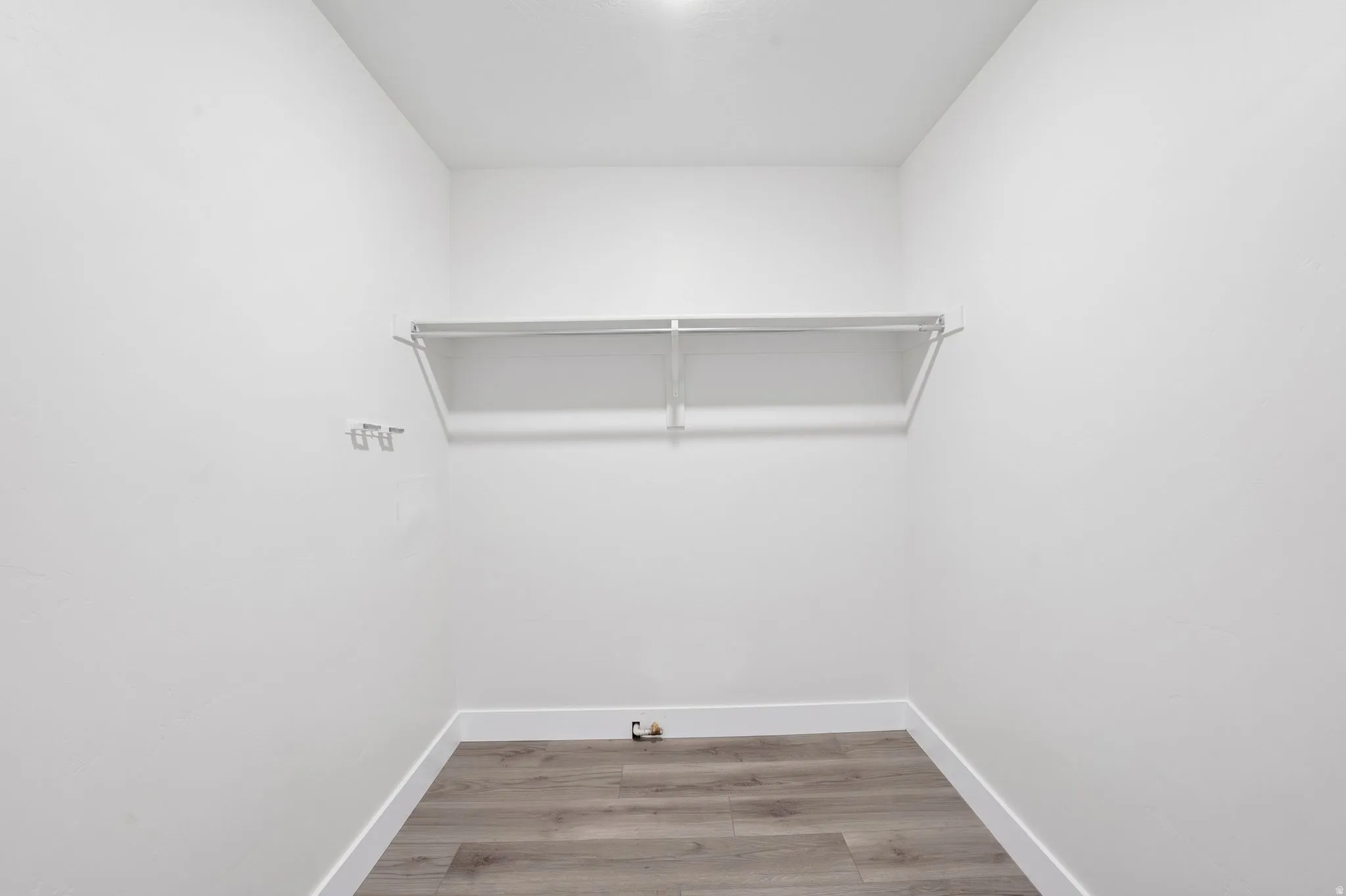 Closet space featuring wood-finish flooring, white walls, and a white wire shelving system