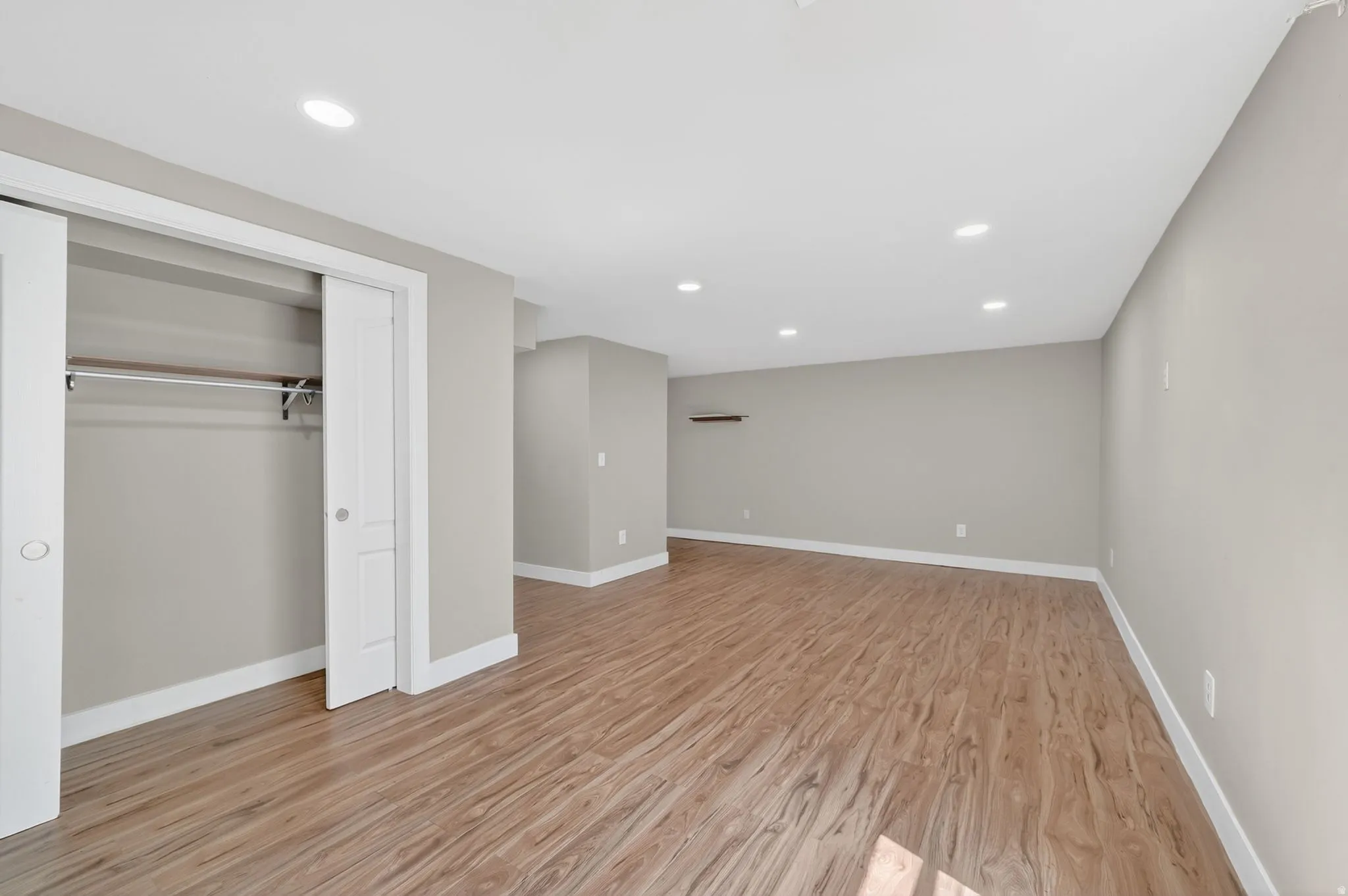 Spacious room featuring wood-finish flooring, recessed lighting, and a built-in closet with sliding doors