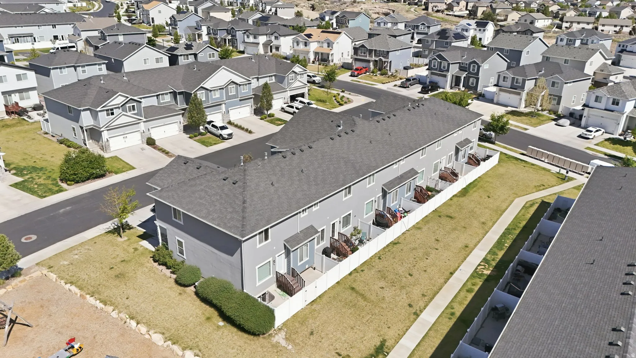 Townhome-style residences featuring light gray siding and dark gray shingle roofing