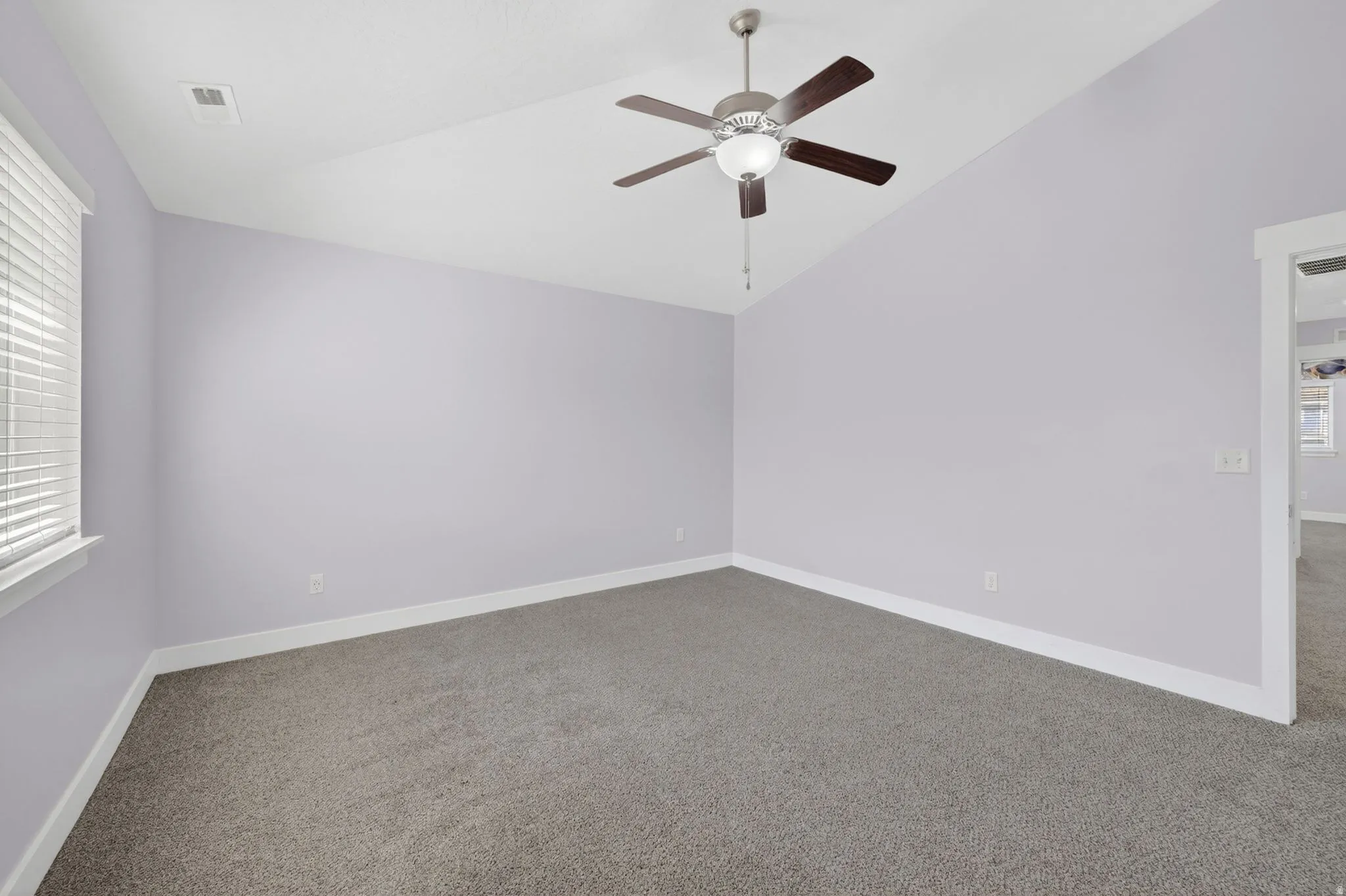 Carpeted room featuring a ceiling fan with integrated lighting, a single window with horizontal blinds, white baseboards, and a neutral wall color