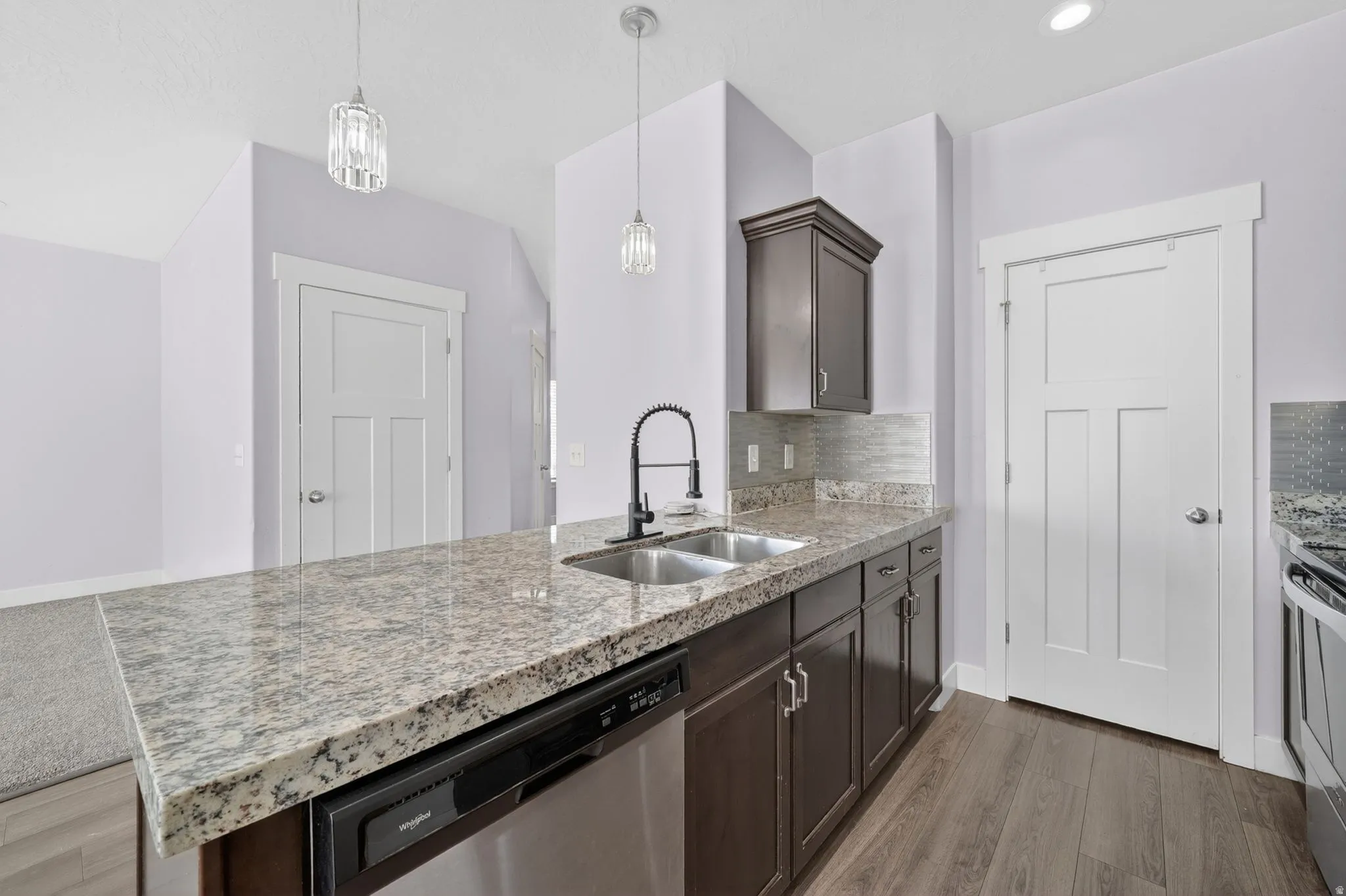 Kitchen island with granite-style countertop, stainless steel sink, and black pull-down faucet