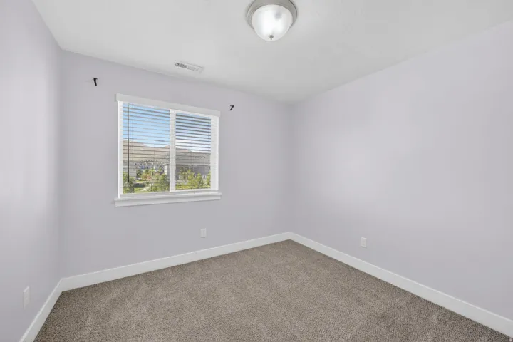 Interior room featuring light-colored walls, carpet flooring, a window with blinds, and a flush-mount ceiling light fixture