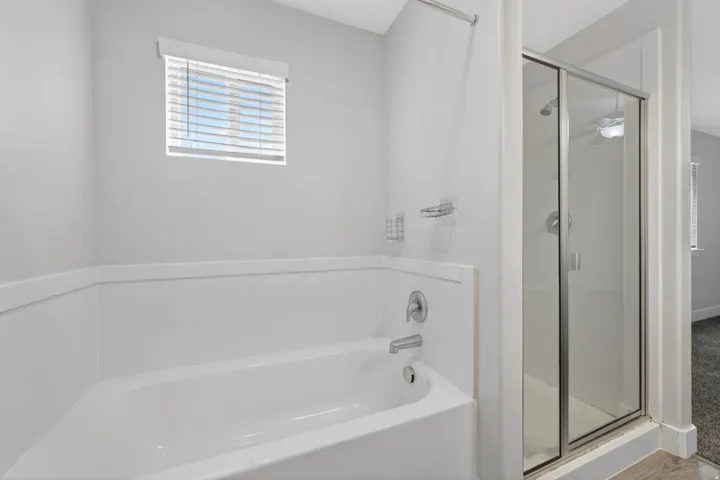 Bathroom featuring a built-in tub and separate glass-enclosed shower with chrome fixtures