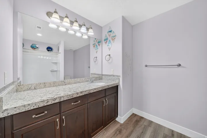 Bathroom featuring a lengthy dark wood-finish vanity with a light speckled countertop and a full-width mirror