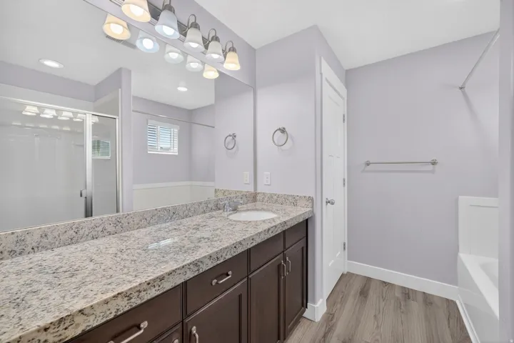 Expansive vanity with a light speckled countertop, dual under-mount sinks, and dark wood-finish cabinetry