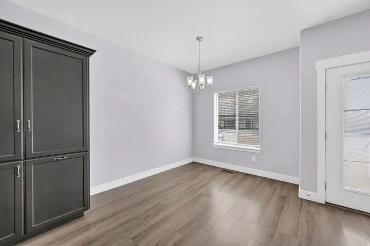 Dining area with dark wood-finish built-in cabinetry, wood-finish flooring, a window with blinds, and an overhead chandelier