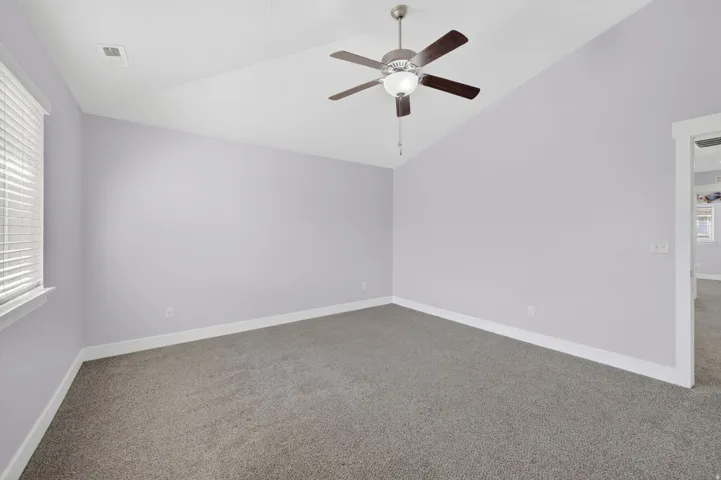 Carpeted room featuring a ceiling fan with integrated lighting, a single window with horizontal blinds, white baseboards, and a neutral wall color