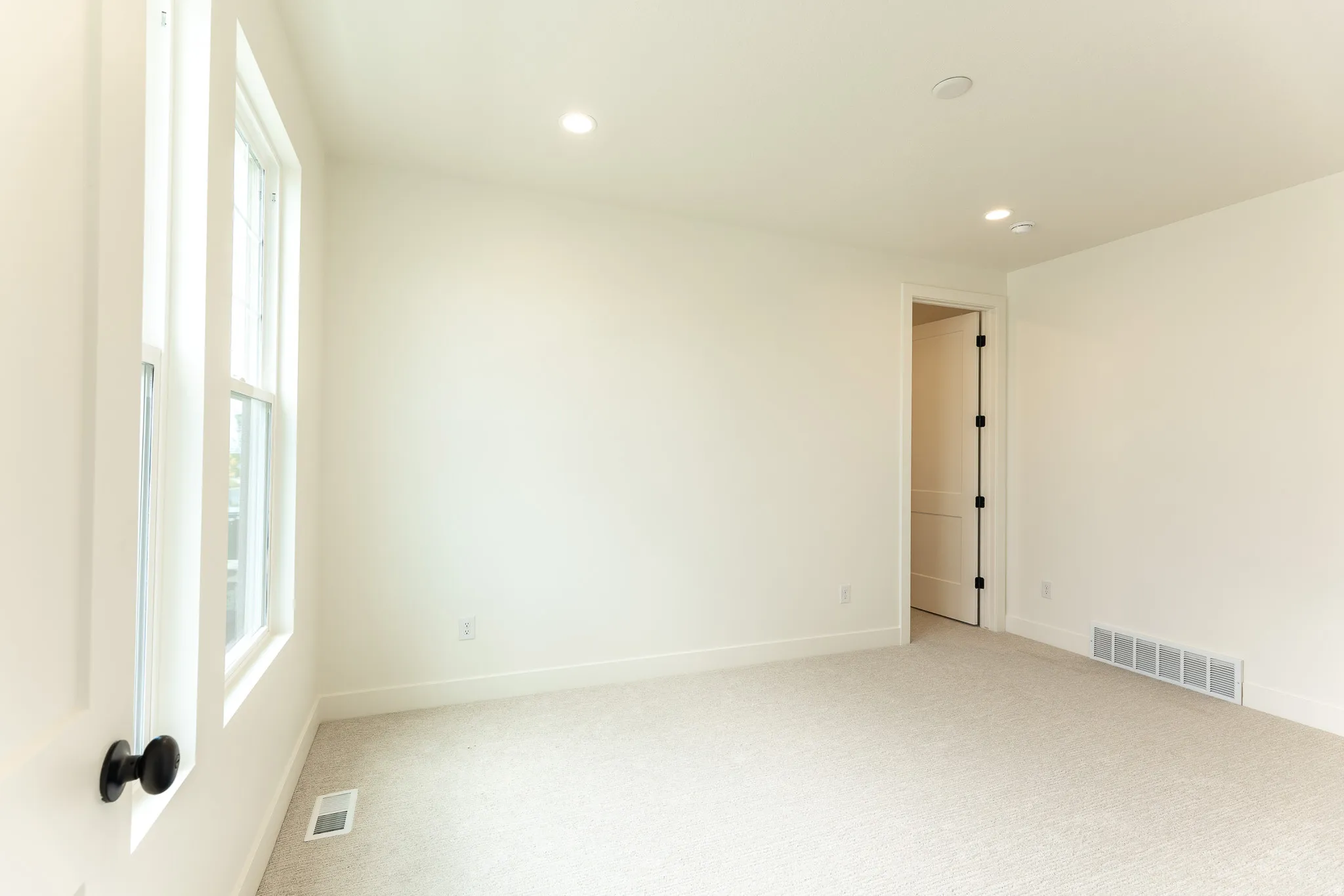 Primary bedroom on Main featuring neutral carpeting, a double-hung window, and recessed lighting