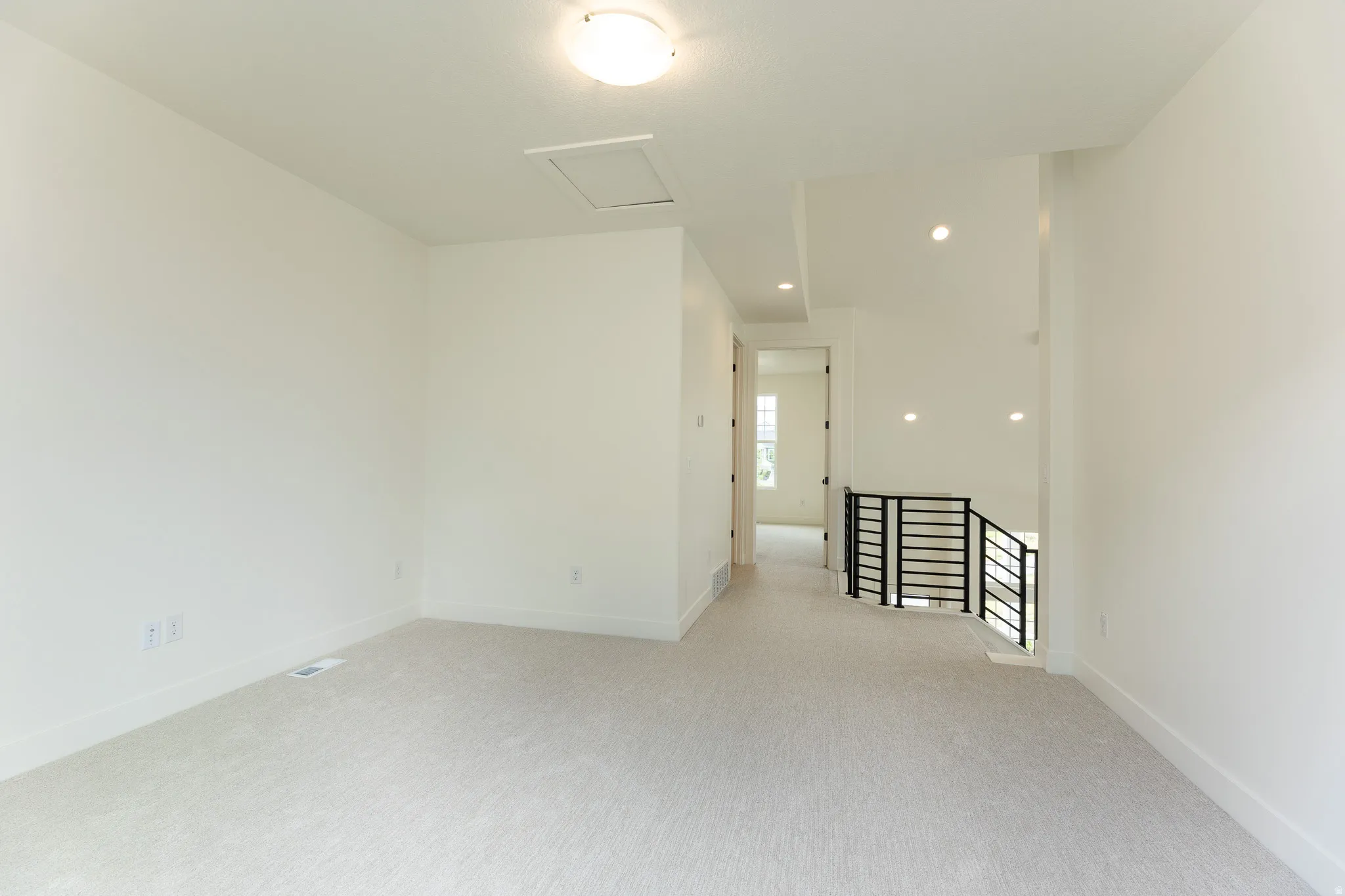 Carpeted interior space with white walls, a contemporary black metal stair railing, recessed lighting, and a flush mount ceiling fixture