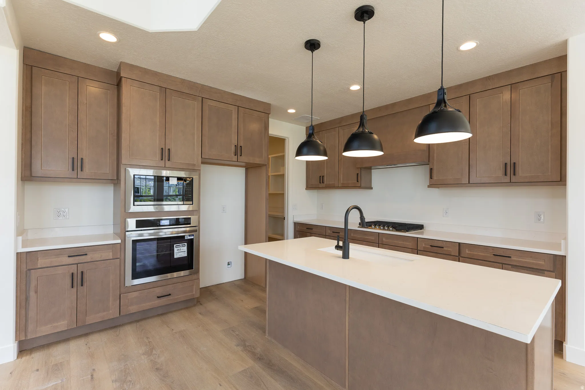 Contemporary kitchen featuring light wood-finish cabinetry, light-toned countertops, and wood-finish flooring