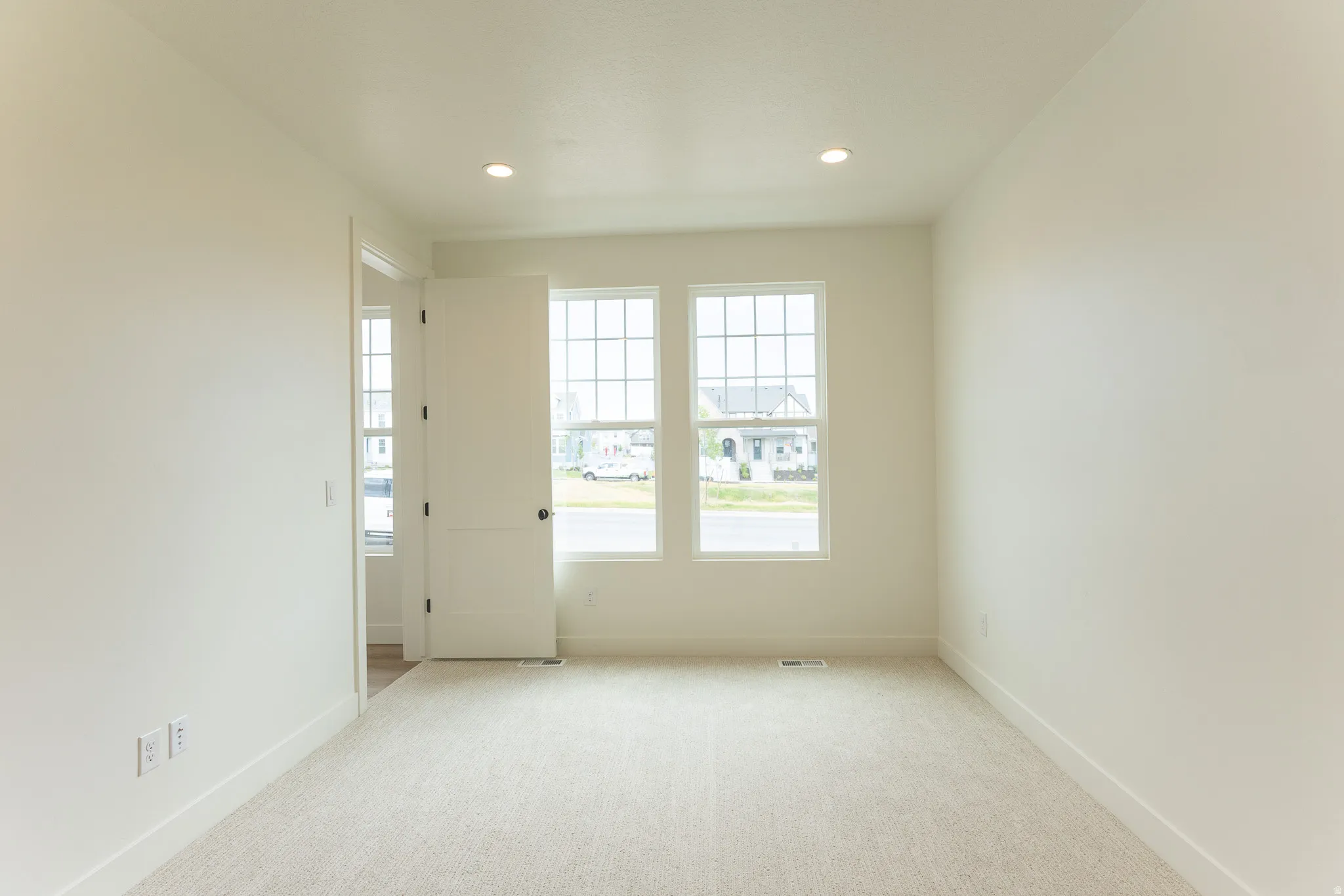 Primary bedroom on Main featuring two grid-pattern windows, recessed lighting, and white baseboards